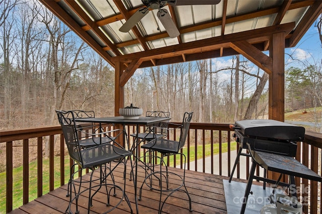 wooden terrace with outdoor dining space and ceiling fan