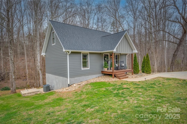 view of front of home featuring cooling unit, a porch, a front lawn, and roof with shingles