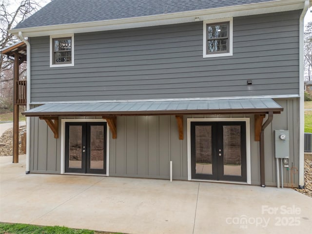 rear view of house with a patio area, french doors, and roof with shingles