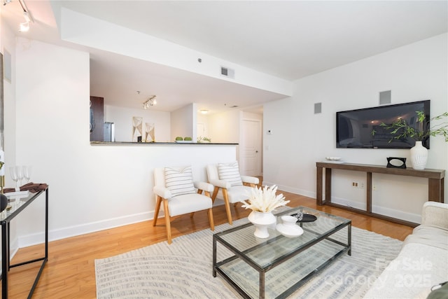 living room featuring light wood-style flooring, baseboards, and visible vents