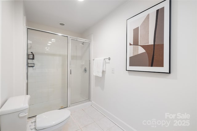 bathroom featuring tile patterned floors, baseboards, toilet, and a stall shower