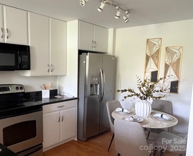 1320 Fillmore St Unit 419, Charlotte, NC 28203 - kitchen with stainless steel appliances, light wood finished floors, white cabinetry, dark countertops, and track lighting