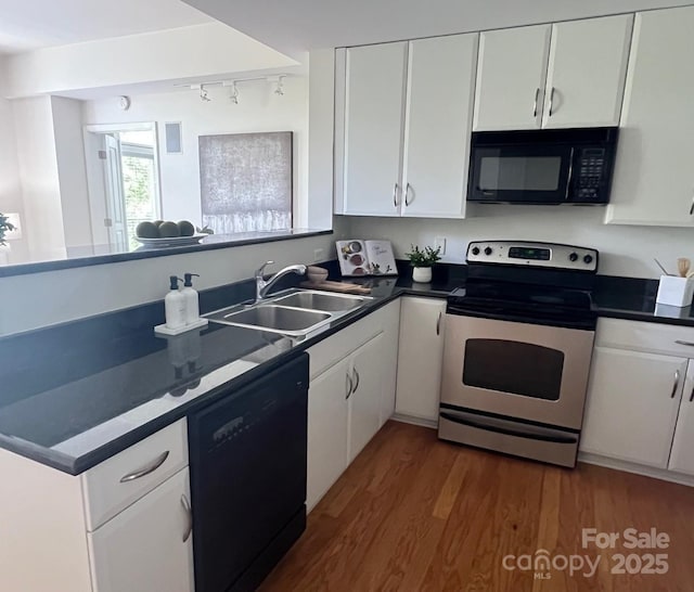 1320 Fillmore St Unit 419, Charlotte, NC 28203 - kitchen featuring black appliances, track lighting, white cabinetry, wood finished floors, and dark countertops