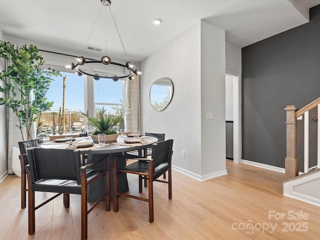 dining room with stairway, baseboards, visible vents, and light wood finished floors