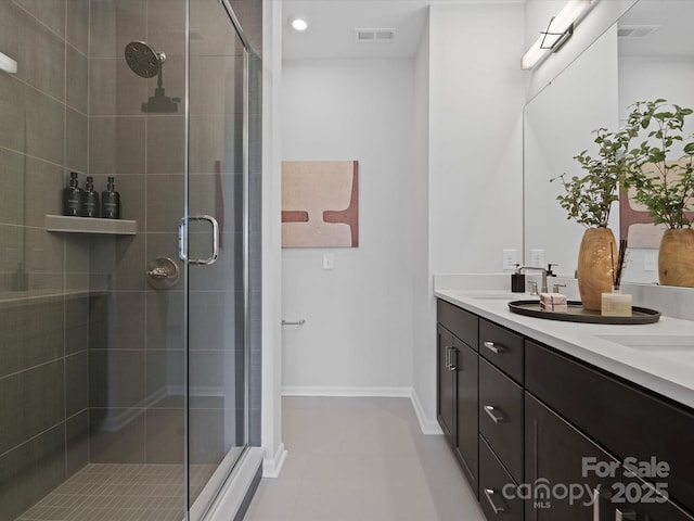 bathroom featuring double vanity, visible vents, baseboards, and a stall shower