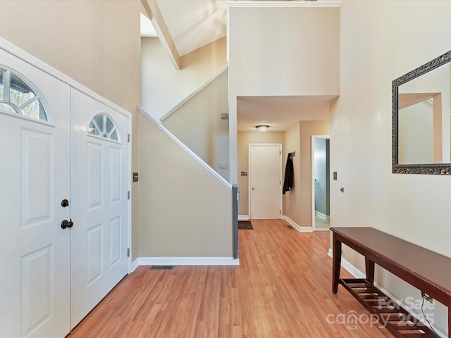 entryway with a high ceiling, baseboards, and light wood finished floors