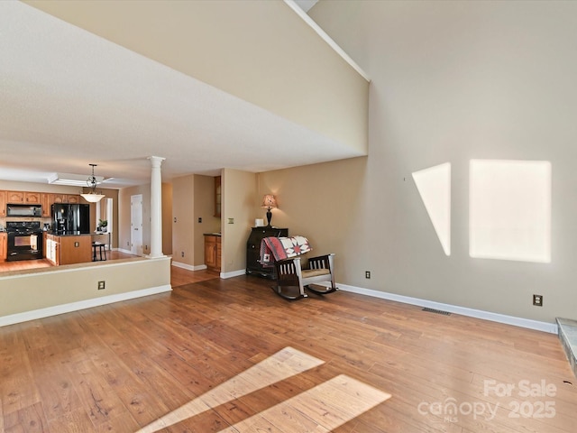 interior space with light wood finished floors, visible vents, baseboards, and ornate columns