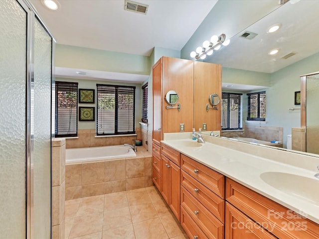 bathroom featuring tile patterned flooring, visible vents, a garden tub, and a sink