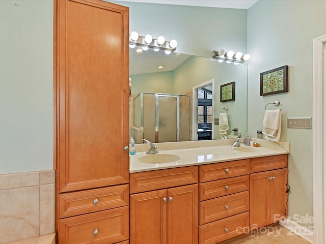 bathroom with a sink, double vanity, a shower stall, and tile patterned floors