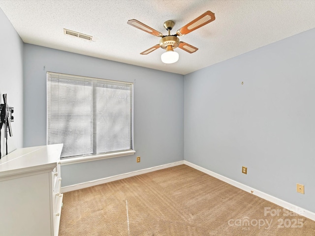 spare room featuring visible vents, light colored carpet, baseboards, and a ceiling fan