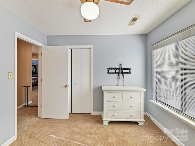 bedroom featuring light colored carpet, a textured ceiling, and baseboards