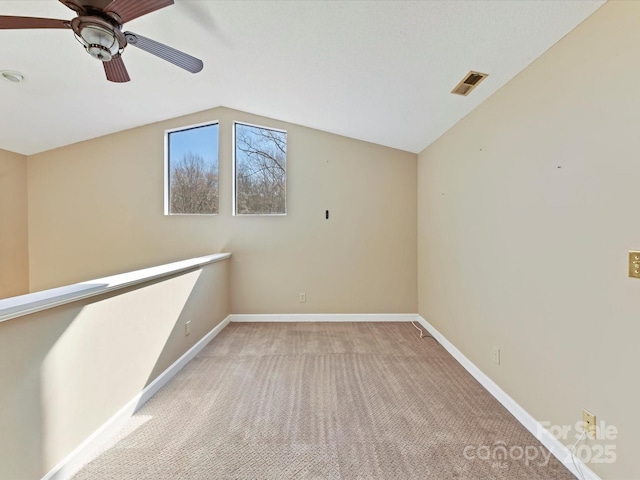 empty room featuring visible vents, light carpet, lofted ceiling, baseboards, and ceiling fan