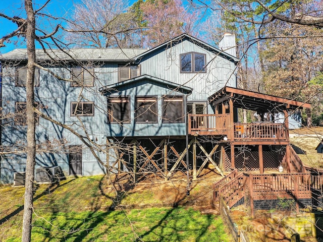 back of house with a wooden deck, stairs, a lawn, a chimney, and a sunroom