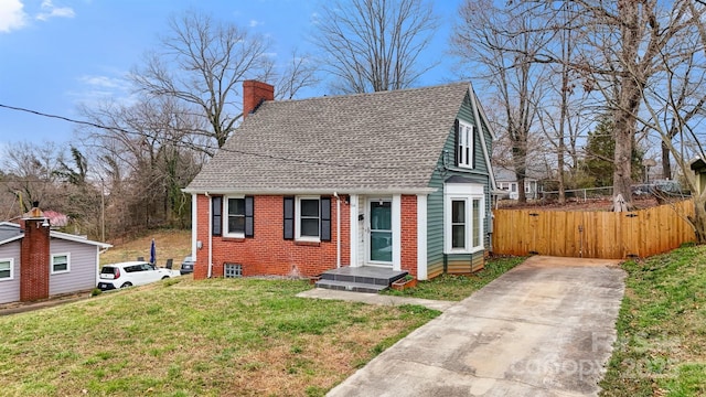 view of front facade with fence, roof with shingles, a front yard, brick siding, and a chimney