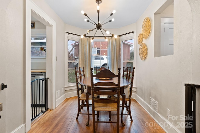 dining space featuring visible vents, baseboards, an inviting chandelier, and hardwood / wood-style flooring