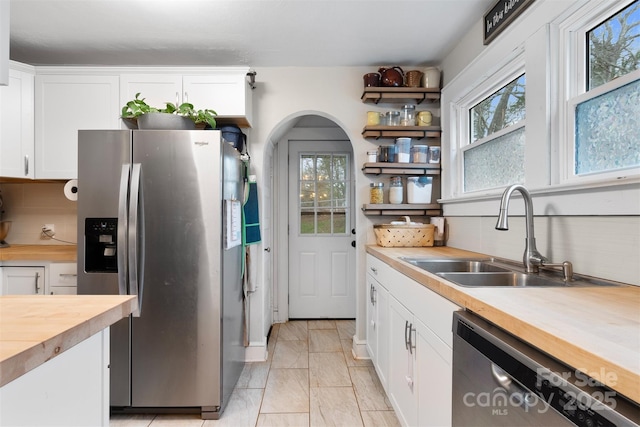 kitchen featuring a sink, wood counters, white cabinetry, stainless steel appliances, and decorative backsplash