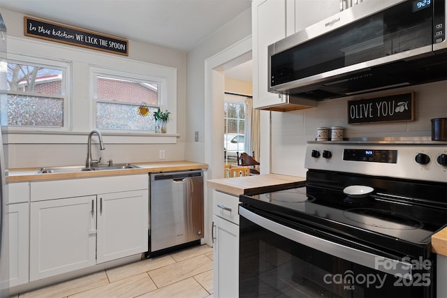 kitchen featuring decorative backsplash, wooden counters, appliances with stainless steel finishes, and a sink