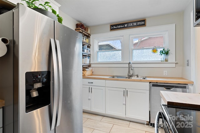 kitchen featuring a sink, white cabinetry, stainless steel fridge, butcher block counters, and dishwasher