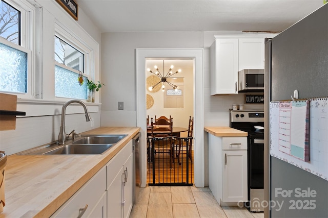 kitchen featuring a sink, stainless steel appliances, backsplash, and white cabinetry