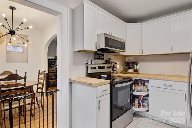 kitchen with decorative light fixtures, white cabinetry, stainless steel appliances, an inviting chandelier, and butcher block counters