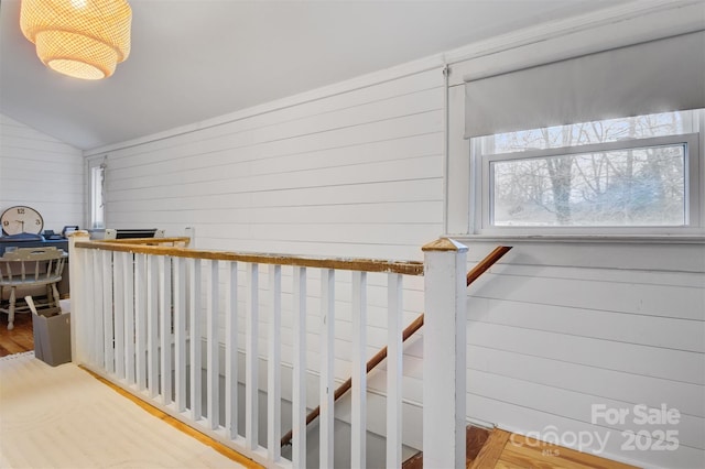 stairs featuring wood finished floors, wood walls, and vaulted ceiling