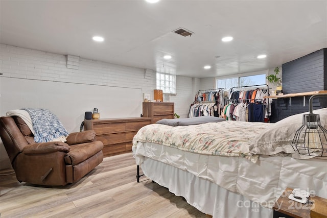 bedroom featuring visible vents, recessed lighting, brick wall, and wood finished floors