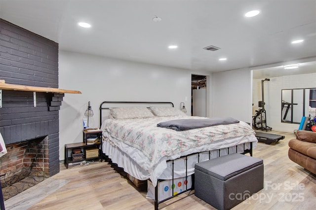 bedroom with recessed lighting, visible vents, wood finished floors, and a fireplace