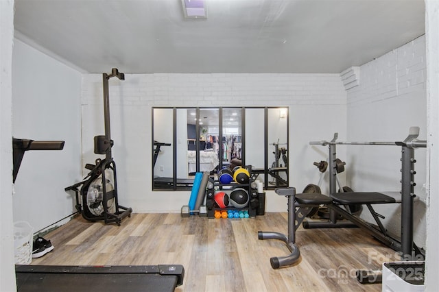 exercise room featuring wood finished floors and brick wall