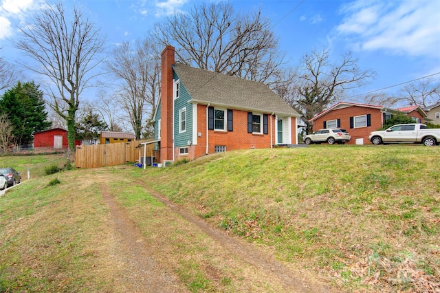 view of front of home with fence, a chimney, a front lawn, dirt driveway, and brick siding