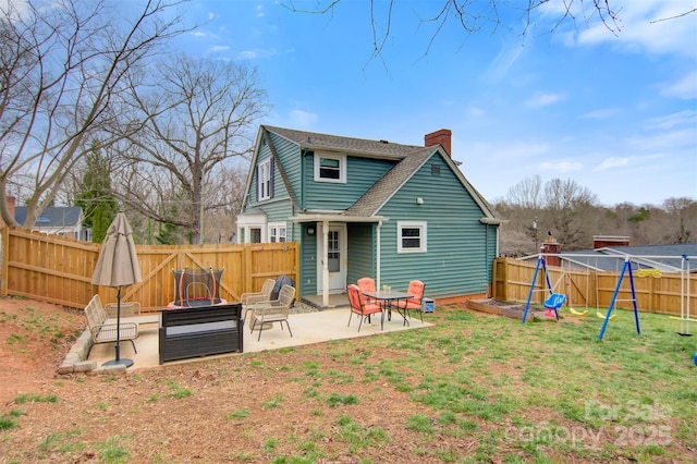 back of property featuring a fenced backyard, a playground, a yard, a chimney, and a patio area