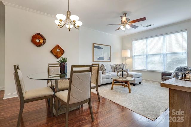 dining space featuring ceiling fan with notable chandelier, dark wood-style floors, visible vents, and ornamental molding