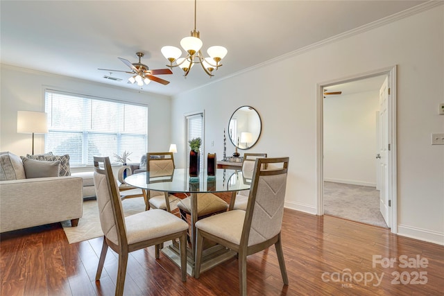 dining room featuring ceiling fan with notable chandelier, crown molding, wood finished floors, and baseboards