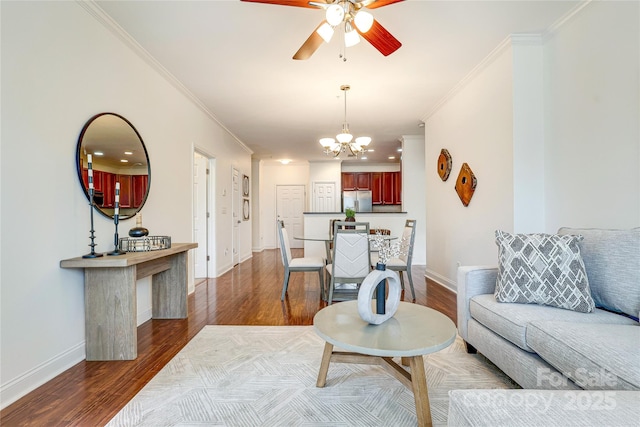 living area featuring dark wood finished floors, ceiling fan with notable chandelier, and crown molding