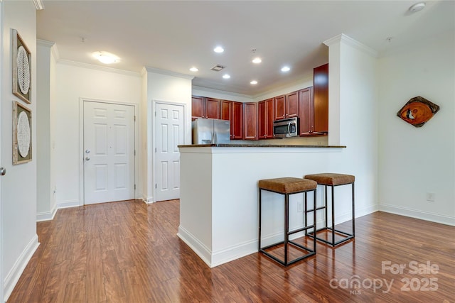 kitchen featuring visible vents, dark countertops, dark wood finished floors, stainless steel appliances, and crown molding