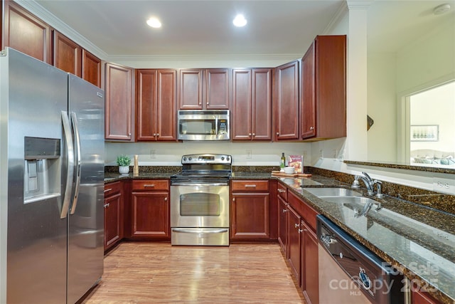 kitchen featuring a sink, stainless steel appliances, light wood-style floors, and dark stone countertops