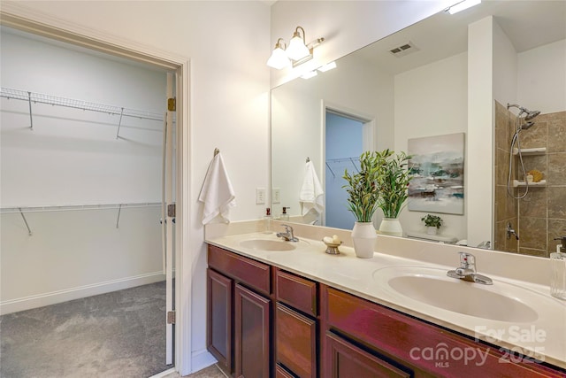 bathroom featuring a walk in closet, double vanity, and a sink