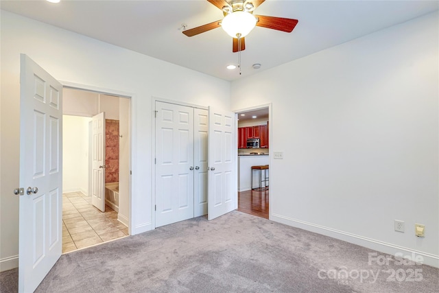 unfurnished bedroom featuring baseboards, a closet, and light carpet