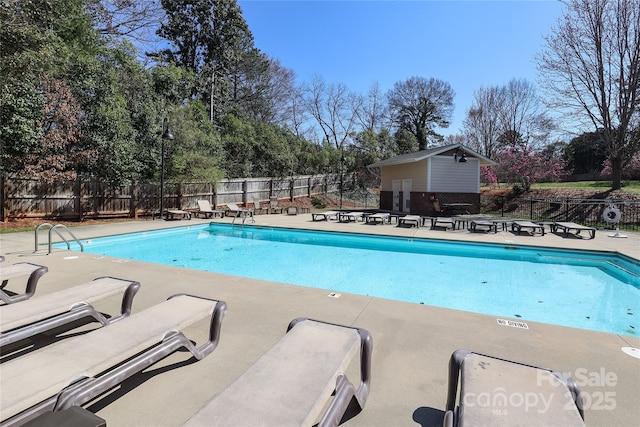 pool featuring an outbuilding, fence, and a patio area