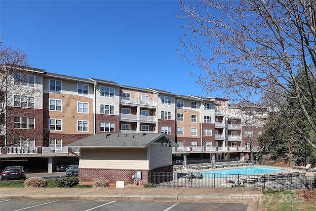 view of property featuring a community pool and fence