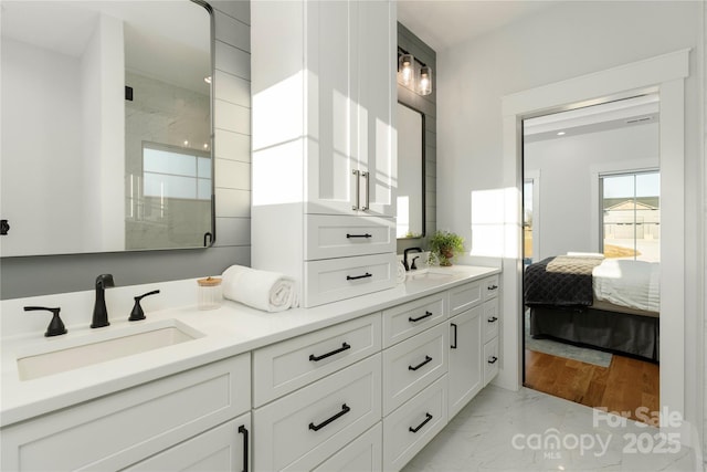 ensuite bathroom featuring a sink, marble finish floor, a shower stall, and double vanity