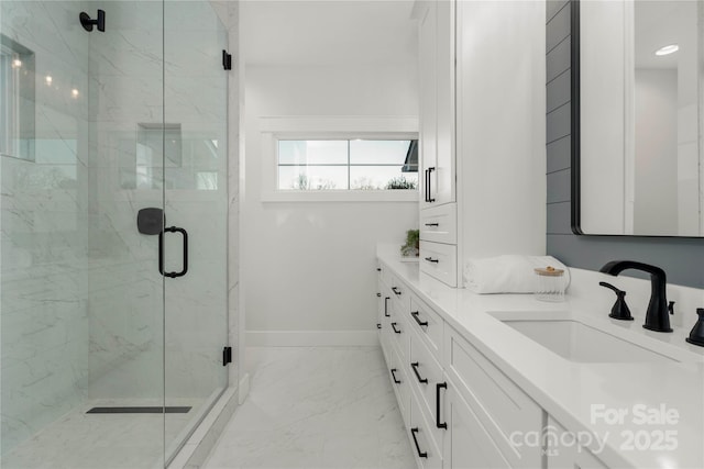 bathroom featuring baseboards, a marble finish shower, double vanity, a sink, and marble finish floor