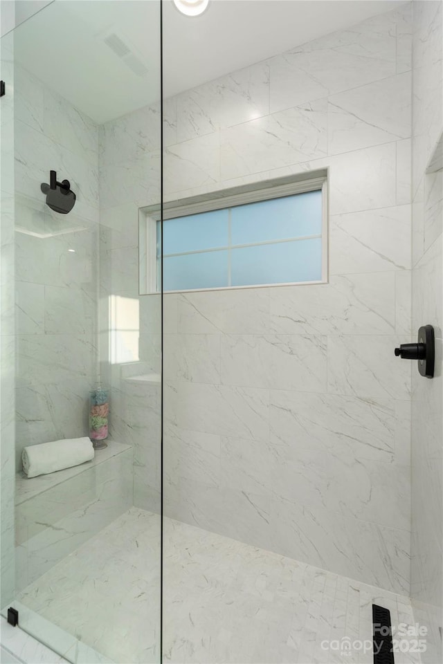 full bathroom with a wealth of natural light, visible vents, and a marble finish shower