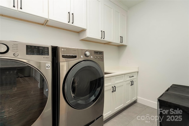 laundry room featuring light tile patterned floors, cabinet space, baseboards, and separate washer and dryer