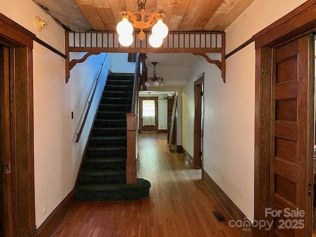 corridor with visible vents, wood ceiling, stairs, an inviting chandelier, and wood finished floors