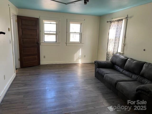 living room with baseboards and dark wood-type flooring