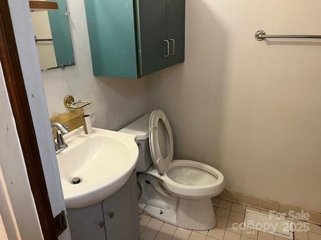 half bath with vanity, tile patterned floors, and toilet