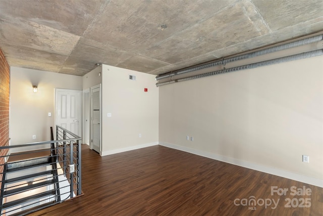 empty room with wood finished floors, visible vents, and baseboards