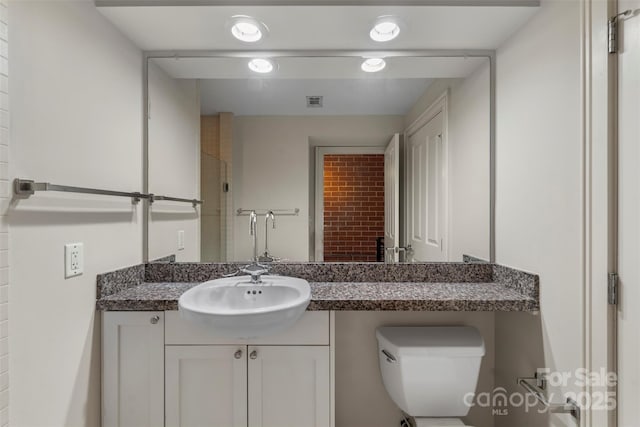 bathroom featuring vanity, toilet, visible vents, and walk in shower