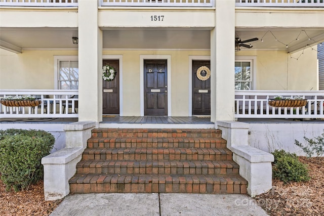 property entrance featuring covered porch, a ceiling fan, and stucco siding