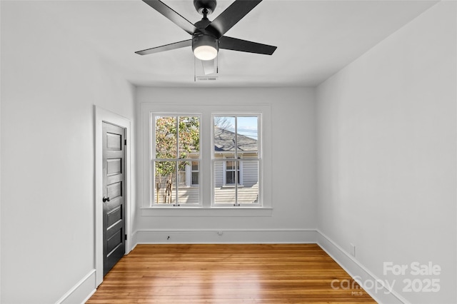 empty room with visible vents, light wood-style flooring, baseboards, and ceiling fan